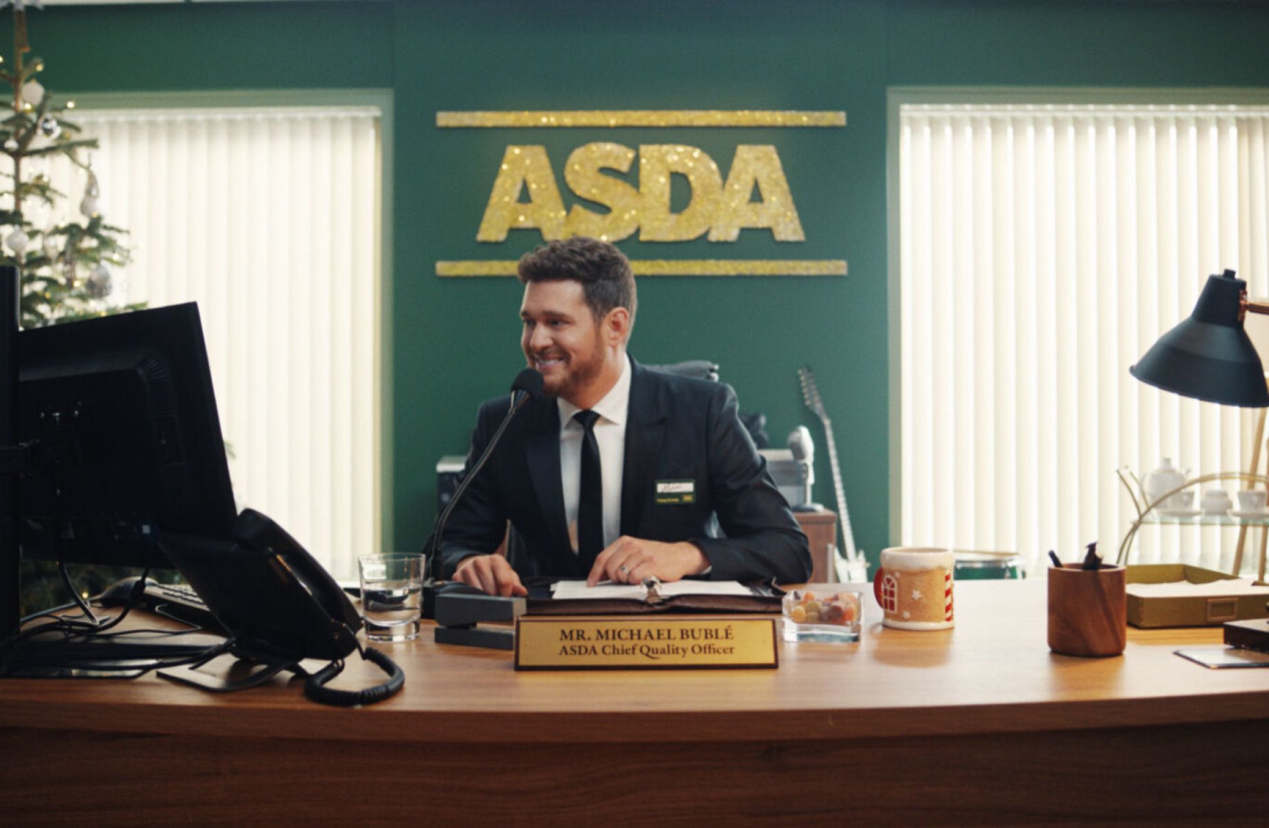 Man sitting on a desk. Asda sign on the back